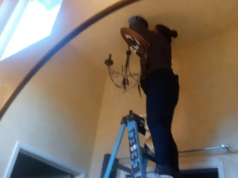 Electrician installing a chandelier in a Granger residence